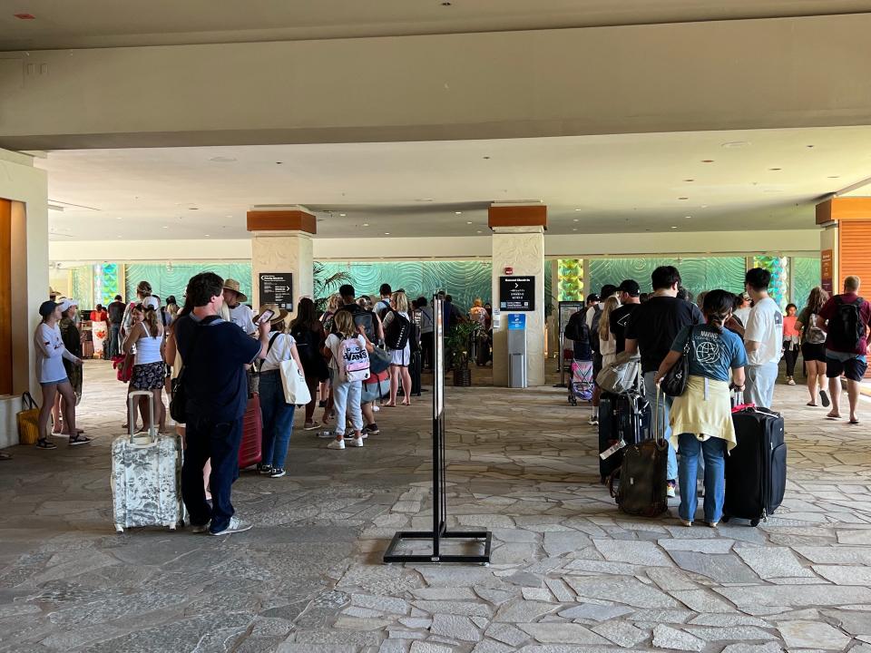 A crowded hotel lobby with long lines waiting to approach the front desk.