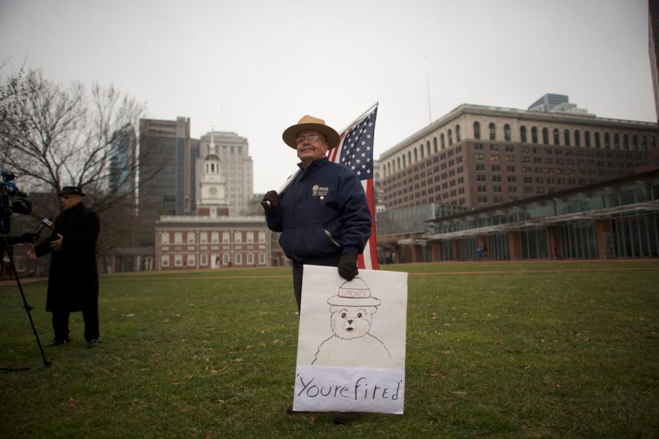 PHILADELPHIA, PA - JANUARY 08:  David Fitzpatrick, 64, a Park Ranger, holds an American flag and a placard stating "You're fired" with "Smokey the Bear," after a protest rally with furloughed federal workers and area elected officials in front of Independence Hall on January 8, 2019 in Philadelphia, Pennsylvania.  The government shutdown, now lasting 18 days, marks the second longest United States in history, affecting about 800,000 federal employees.  (Photo by Mark Makela/Getty Images) ORG XMIT: 775278689 ORIG FILE ID: 1079379668