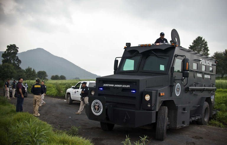 Mexican police officers block a road leading to a park in the municipality of Tlalmanalco, some 30 km southeast of Mexico City on August 22, 2013, where at least 7 bodies were discovered in a mass grave