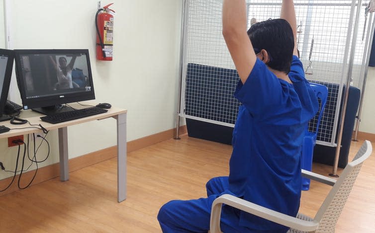 A medical professional guiding a patient through rehabilitation exercises over webcam.