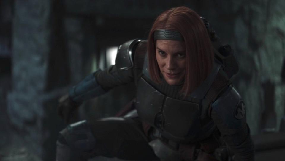 Bo-Katan without her helmet smiles while on the ground on The Mandalorian