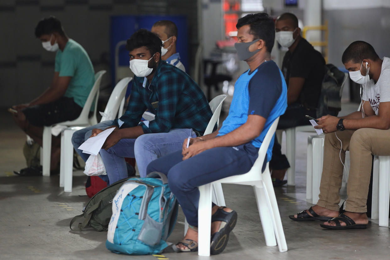 SINGAPORE - APRIL 27:  Foreign workers wearing protective mask wait to be transferred from their dormitory on April 27, 2020 in Singapore. Singapore is now battling to control a huge outbreak in the coronavirus (COVID-19) local transmission cases among the migrant workers.  (Photo by Suhaimi Abdullah/Getty Images)