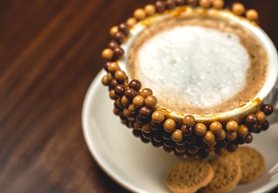 A cafe con leche with a sweet rim of chocolate arequipe pirulin at Senora Arepa restaurant in Louisville.