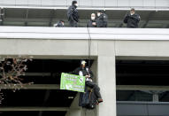 An activist hangs on an airport building to protest against the opening of the new Berlin-Brandenburg-Airport 'Willy Brandt' in Berlin, Germany, Saturday, Oct. 31, 2020. Berlin's new airport opens after years of delays and cost overruns. (AP Photo/Michael Sohn)