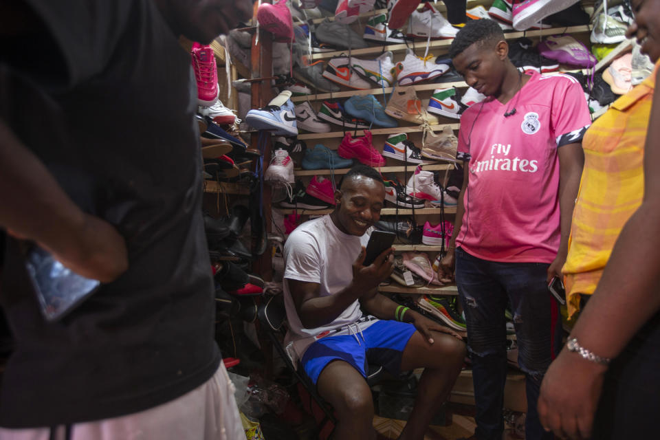 Jhon Celestin, deported from the United States two days earlier, talks with a friend in Chile while shopping for sneakers in Port-au-Prince, Haiti, Friday, Sept. 24, 2021. Celestin's new plan is to return to Chile, where he built homes as a construction worker after obtaining a visa. (AP Photo/Joseph Odelyn)