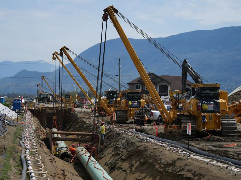  Workers lay pipe during construction of the Trans Mountain pipeline expansion on farmland, in Abbotsford, B.C., on May 3, 2023.
