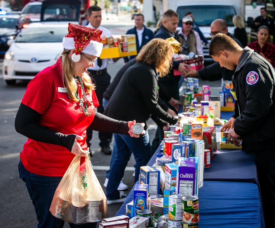 Stacie Causey, left, fills a table with canned goods while helping to unload a vehicle with canned and dry food goods on Friday. She was among those helping during the annual Bring the Harvest Home food drive on the downtown square.