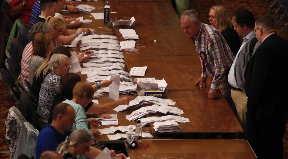 Observers watches as official counters sort votes cast for the European Elections, during counting for the South East England region in Southampton, England, Sunday, May 26, 2019. (AP Photo/Alastair Grant)