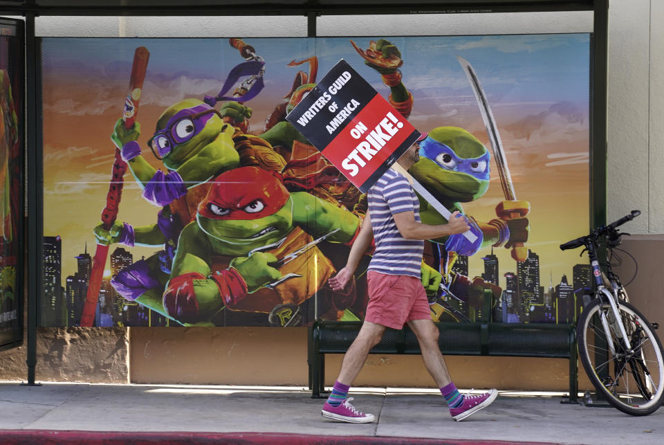 A picketer walks past an advertisement for 