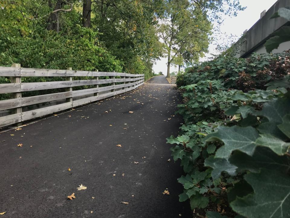 A paved path near Craig Park in Greenwood leads to a pedestrian bridge over Smith Valley Road.
