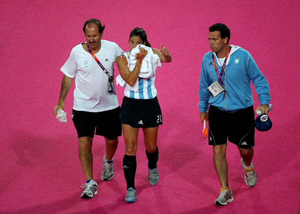 LONDON, ENGLAND - AUGUST 10: Mariela Scarone of Argentina is escorted off the field after being struck in the face during the first half against the Netherlands during the Women's Hockey gold medal match on Day 14 of the London 2012 Olympic Games at Hockey Centre on August 10, 2012 in London, England. (Photo by Daniel Berehulak/Getty Images)