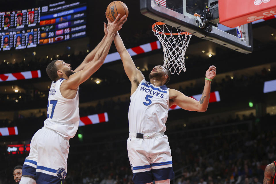 Minnesota Timberwolves center Rudy Gobert (27) and forward Kyle Anderson (5) reach for a rebound in the first half of an NBA basketball game against the Atlanta Hawks, Monday, March 13, 2023, in Atlanta. (AP Photo/Brett Davis)