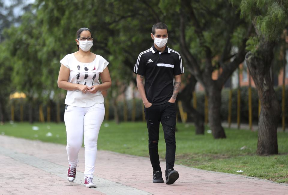 Dionis Palacios and his mother, wearing protective face masks as a precaution against the spread of the new coronavirus, walk side by side in Bogota, Colombia, Monday, May 18, 2020. Palacios, an 18-year-old Venezuelan migrant with no health insurance went to the hospital after experiencing chest pain and said he was taken aback by how many beds were filled. "The hospitals are totally collapsing," he said. (AP Photo/Fernando Vergara)