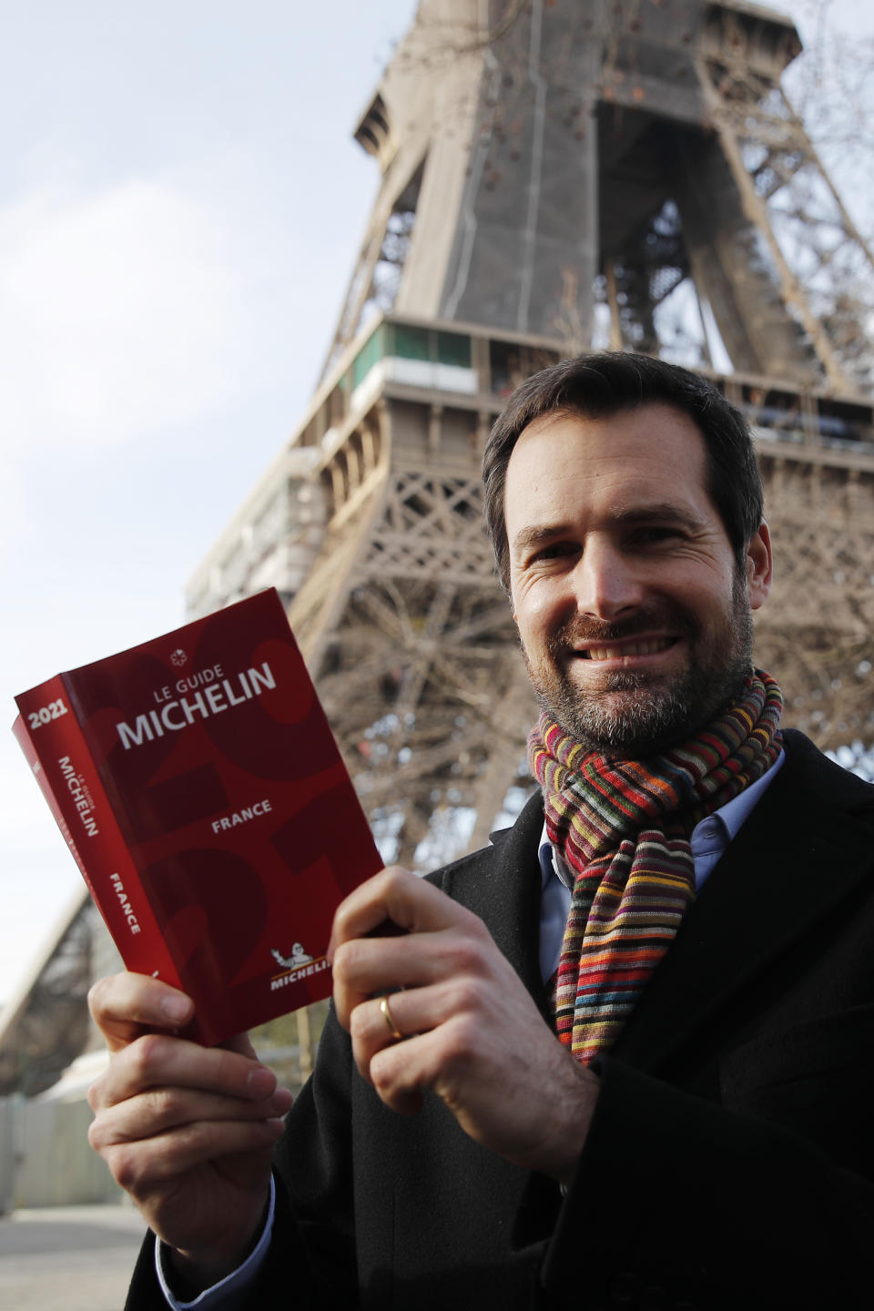 Gwendal Poullennec, head of Le Guide Michelin, poses with the 2021 edition outside the Eiffel Tower, Monday, Jan. 18, 2021 in Paris. Michelin will later announce the 2021 winners in a broadcast from the Eiffel Tower. (AP Photo/Francois Mori)