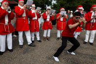 <p>A person takes photos of people dressed as Santa Claus as they meet at the Little Mermaid statue while they take part in the World Santa Claus Congress, an annual event held every summer in Copenhagen, Denmark, July 23, 2018. (Photo: Andrew Kelly/Reuters) </p>