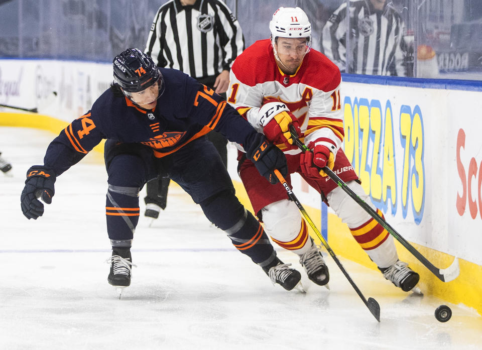 Edmonton Oilers' Ethan Bear (74) and Calgary Flames' Mikael Backlund (11) battle for the puck during the first period of an NHL hockey game, Thursday, April 29, 2021 in Edmonton, Alberta. (Jason Franson/Canadian Press via AP)