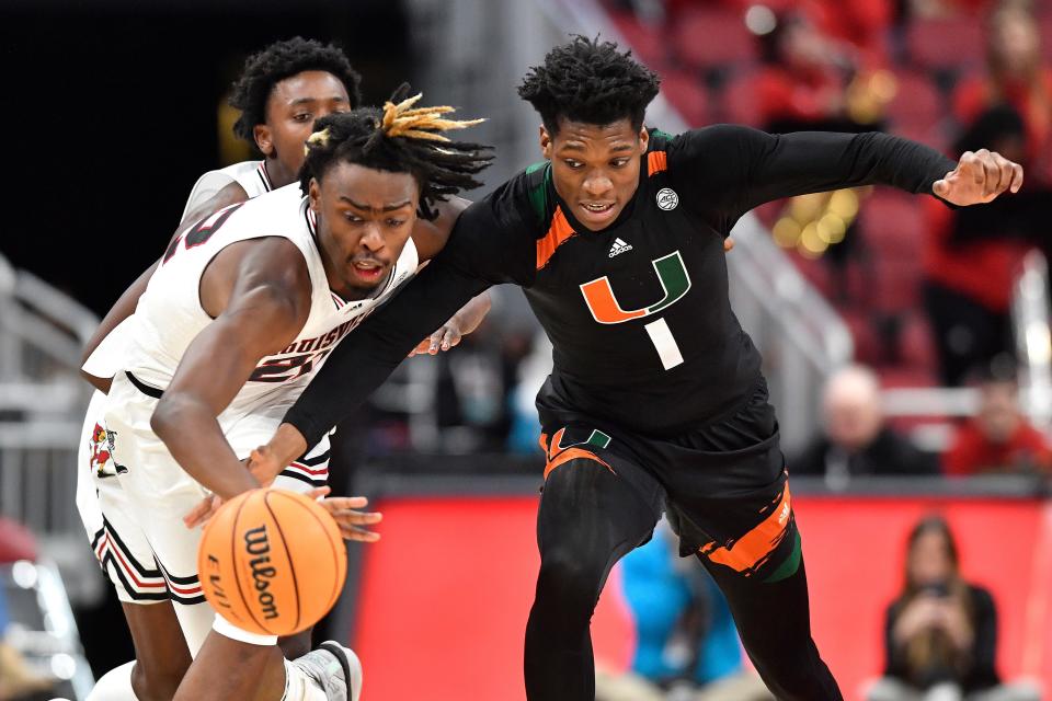 Louisville forward Kamari Lands battles Miami forward Anthony Walker (1) for a loose ball during the second half of an NCAA college basketball game in Louisville, Ky., Sunday, Dec. 4, 2022. Miami won 80-53. (AP Photo/Timothy D. Easley)