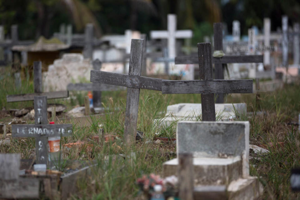 Crosses stand in a cemetery in Tawau, Malaysia, on Sunday, Dec. 9, 2018, where the grandchild and husband of Anna, 45, a migrant worker from Indonesia, are buried. She said her son, whose newborn baby was buried next to the infant's grandfather and other migrant workers, had inherited his father's job working on a palm oil plantation. He is the family's main breadwinner. (AP Photo/Binsar Bakkara)