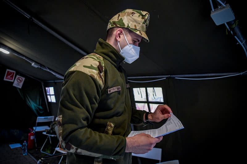 Hungarian epee world champion Gergely Siklosi checks papers as he volunteers at a vaccination centre in Budapest