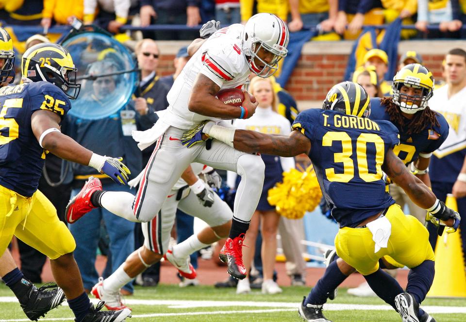 Ohio State Buckeyes quarterback Braxton Miller (5) splits Michigan Wolverines linebacker Kenny Demens (25) and Michigan Wolverines safety Thomas Gordon (30) during a touchdown run in the 2nd quarter during their NCAA college football game in Michigan Stadium, Ann Arbor, Michigan November 26, 2011. (Dispatch photo by Kyle Robertson)