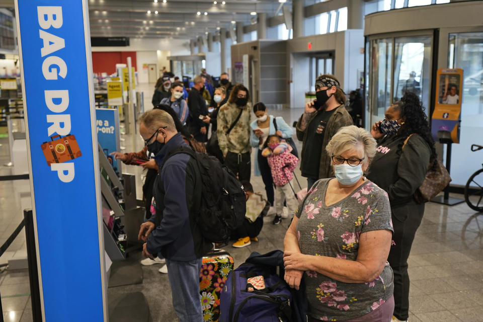 Vickie Lechuk, right, waits in line to check baggage at Cleveland Hopkins International Airport, Wednesday, Nov. 25, 2020, in Cleveland. Lecuk is traveling to Tampa, Florida. (AP Photo/Tony Dejak)