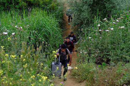 People walk through fields after they were sent out during a police operation to evacuate a makeshift camp at the Greek-Macedonian border near the village of Idomeni, Greece, May 25, 2016. REUTERS/Marko Djurica