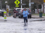 In this Oct. 11, 2019, photo, a woman jogs through a flooded street in Bay Head, N.J. Bay Head is studying options to prevent, or at least reduce, incidents of so-called “sunny day” flooding caused by tides and rising sea levels, as well as major storm-related floods. New Jersey's Department of Environmental Protection and the U.S. Army Corps of Engineers have proposed a massive $16 billion plan to address back bay flooding along the shore. (AP Photo/Wayne Parry)