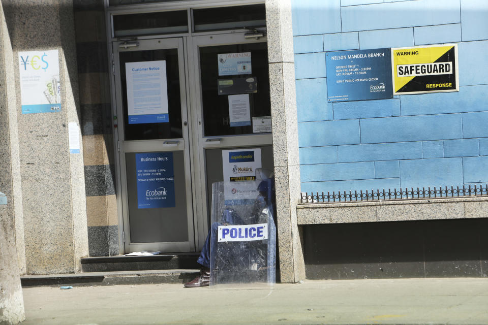 A policeman sits outside a closed bank, in Harare, Friday, July, 31, 2020. Zimbabwe's capital, Harare, was deserted Friday, as security agents vigorously enforced the country's lockdown amidst planned protests. Police and soldiers manned checkpoints and ordered people seeking to get into the city for work and other chores to return home. (AP Photo/Tsvangirayi Mukwazhi)