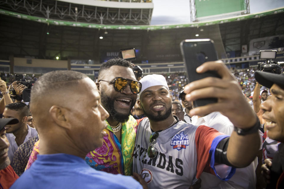 Legendary Boston Red Sox slugger David Ortiz poses for a photo with a fan after making a surprise appearance at the Day of Legends baseball event at the Quisqueya Stadium, in Santo Domingo, Dominican Republic, Sunday, Dec. 8, 2019. The Dominican-American retired professional baseball player was shot in the back in his native country six months ago by a hired gunman who drove up on a motorcycle and fired at close range, hitting him in the torso. They said the intended target was another man. (AP Photo/Tatiana Fernandez)