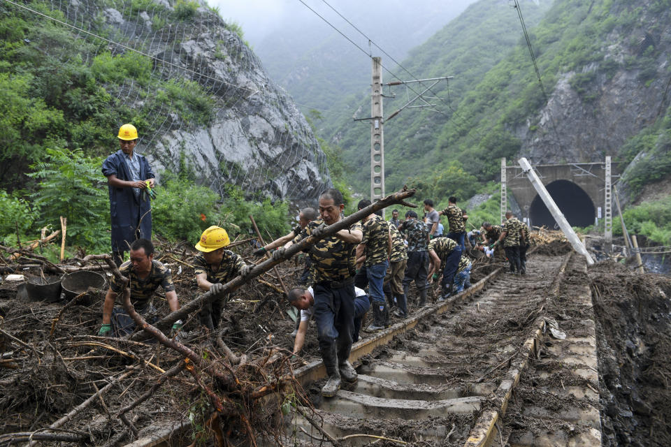 In this photo released by Xinhua News Agency, workers remove fallen debris from a railway track at a flood hit Village in Mentougou district on the outskirts of Beijing on Tuesday, Aug. 1, 2023. China's capital has recorded its heaviest rainfall in at least 140 years over the past few days after being deluged with heavy rains from the remnants of Typhoon Doksuri. (Ju Huanzong/Xinhua via AP)