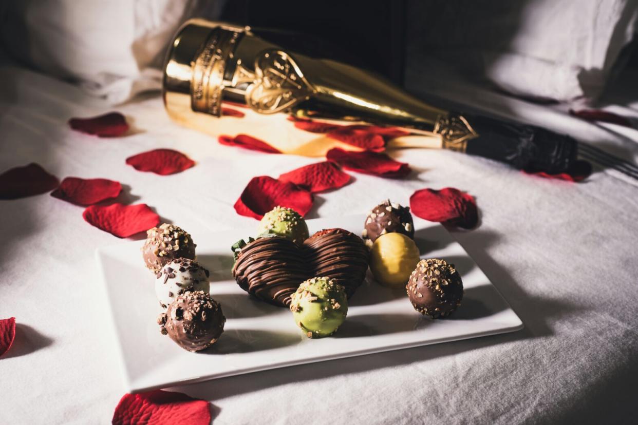 These global Airbnb's are considered some of the best romantic options for couples. pictured: chocolates, rose petals and a bottle on a hotel bed