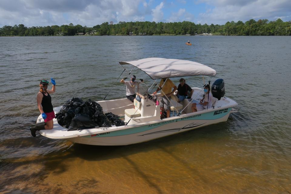 Apalachicola Riverkeeper boat hauling trash bags from large sandbar near Apalachicola.