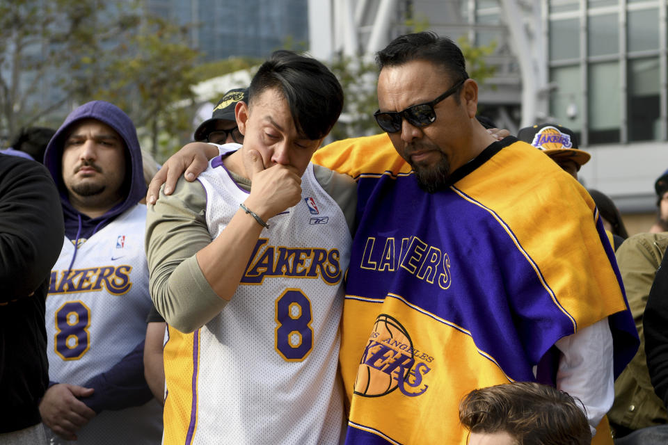 Manuel Alavez Jr., center-left, stands with his father Manuel Alavez Sr. at a memorial for Kobe Bryant near Staples Center Sunday, Jan. 26, 2020, in Los Angeles. Bryant, the 18-time NBA All-Star who won five championships and became one of the greatest basketball players of his generation during a 20-year career with the Los Angeles Lakers, died in a helicopter crash Sunday, Jan. 26, 2020. (AP Photo/Michael Owen Baker)