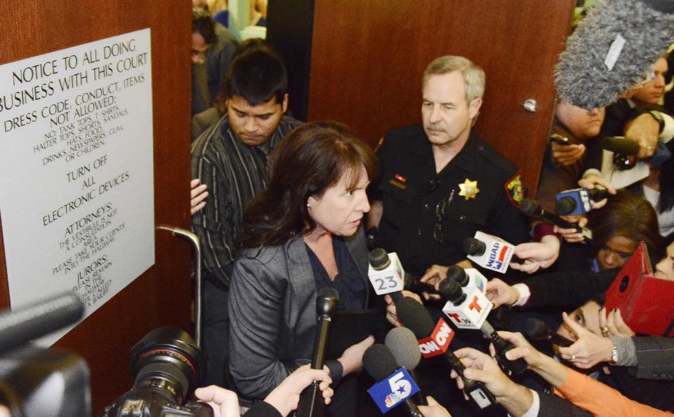 Erick Munoz, rear, husband of Marlise Munoz, stands in the doorway of the courtroom while his attorney Heather L. King answers questions from the media Friday, Jan. 24, 2014 in Fort Worth, Texas. The court ruled in Munoz's favor and to remove his brain-dead pregnant wife from life support. Judge R. H. Wallace Jr. issued the ruling in the case of Marlise Munoz. John Peter Smith Hospital in Fort Worth has been keeping Munoz on life support against her family's wishes. The judge gave the hospital until 5 p.m. CST Monday to remove life support. (AP Photo/Tim Sharp)