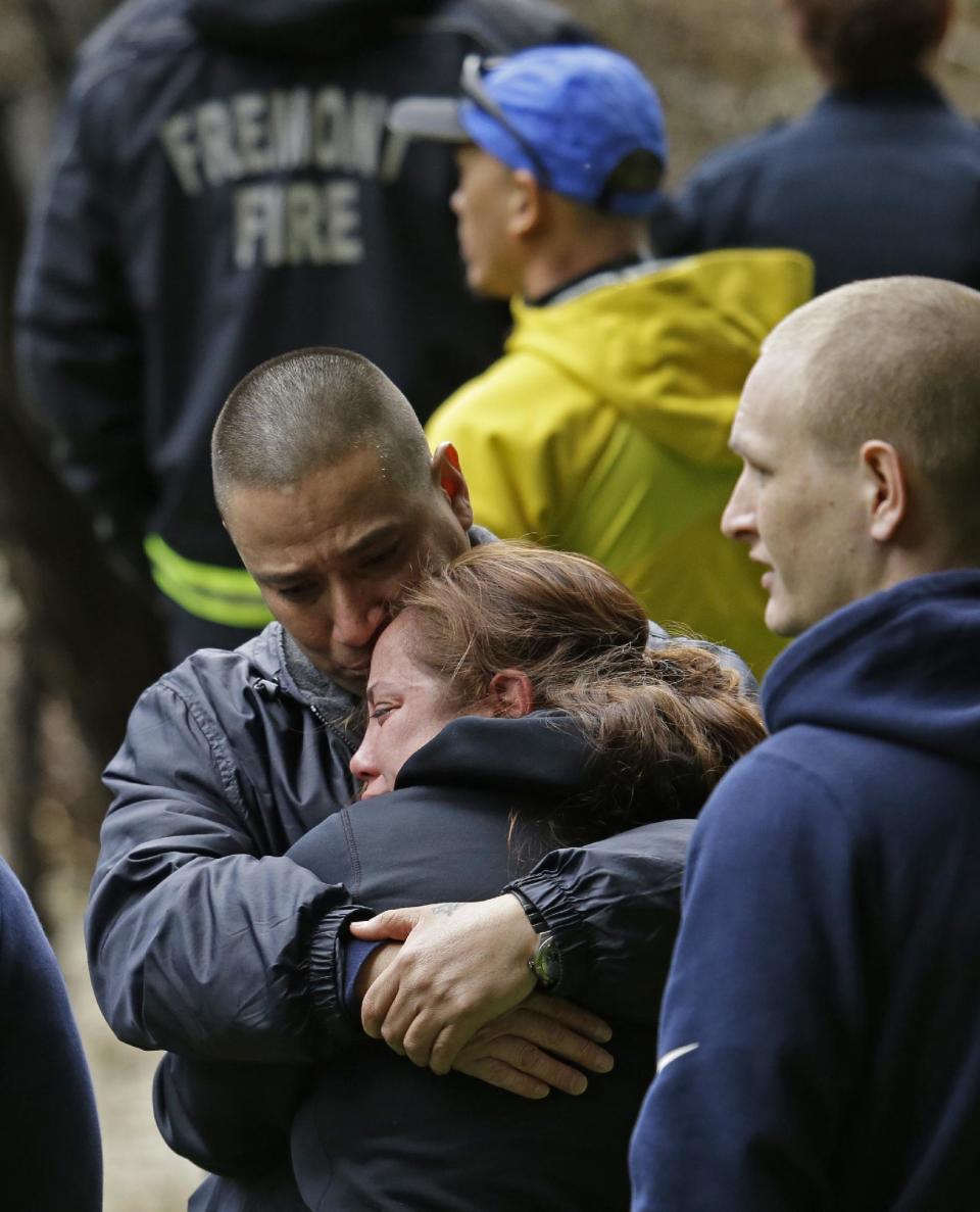 Family members embrace near the banks of Alameda Creek after the site of a submerged vehicle believe to contain the body of a missing 18-year-old woman was located Monday, Jan. 23, 2017 near Fremont, Calif. The unidentified woman's car plunged into rushing waters after colliding with another vehicle on Niles Canyon Road on Saturday. (AP Photo/Ben Margot)