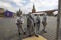 Volunteers wearing face masks, gloves and protective gear to protect against coronavirus, gather to clean an area of an outdoor book market set up at Red Square with GUM, State Department store, left, St. Basil's Cathedral, center, Spasskaya Tower, second with, and the Kremlin Wall, right, in Moscow, Russia, Saturday, June 6, 2020. Muscovites clad in face masks and gloves ventured into Red Square for an outdoor book market, a small sign of the Russian capital's gradual efforts to open up amid coronavirus concerns. (AP Photo/Alexander Zemlianichenko)