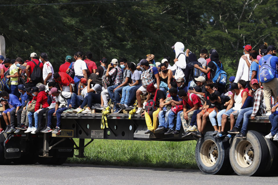 Migrants ride on the back of a freight truck as they move through Santa Rosa de Copan, Honduras, Friday, Jan. 15, 2021, in hopes of reaching the U.S. border. The group quickly dispersed along the heavily-trafficked highway to the border town of Agua Caliente, but estimates of their number ranged from 2,000 to more than twice that. (AP Photo/Delmer Martinez)