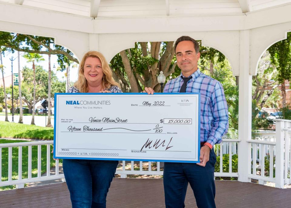 Kara Morgan, CEO of Venice MainStreet, accepts a check for $15,000 from Carlos Puente, vice president of sales and marketing at Neal Communities.