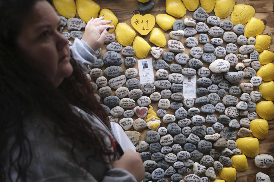 Rima Samman looks for certain names of people who died from coronavirus at Rami's Heart COVID-19 Memorial in Wall Township, N.J., Wednesday, Oct. 27, 2021. The memorial, which started out on a jersey shore beach made of shells and rocks, has found a permanent home at Allaire Community Farm. Started by Rima Samman and named after her brother Rami, who was killed by the coronavirus, it has grown to more than 4,000 victims' names, with dozens of new names added every week. (AP Photo/Seth Wenig)