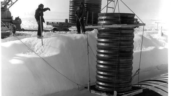 A crane lowers a hatch into a lateral trench of the permanent camp at Camp Century in Greenland.