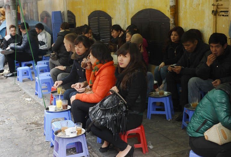 Customers enjoy coffee at a coffee shop set up on a sidewalk in the ancient quarter of Hanoi on January 3, 2013. Vietnamese coffee is traditionally prepared in individual metal drip filters, which produce a very strong, thick liquid often mixed with condensed milk or served black over ice