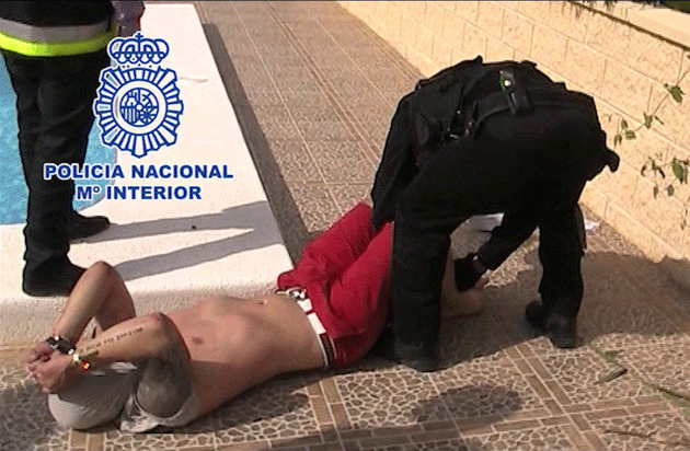 This photo, released by the Spanish National Police and British Serious Organised Crime Agency (SOCA), shows the moment British fugitive Andrew Moran is arrested Friday May 10, 2013, as he relaxed next to the pool of a luxury villa in Alicante, Spain