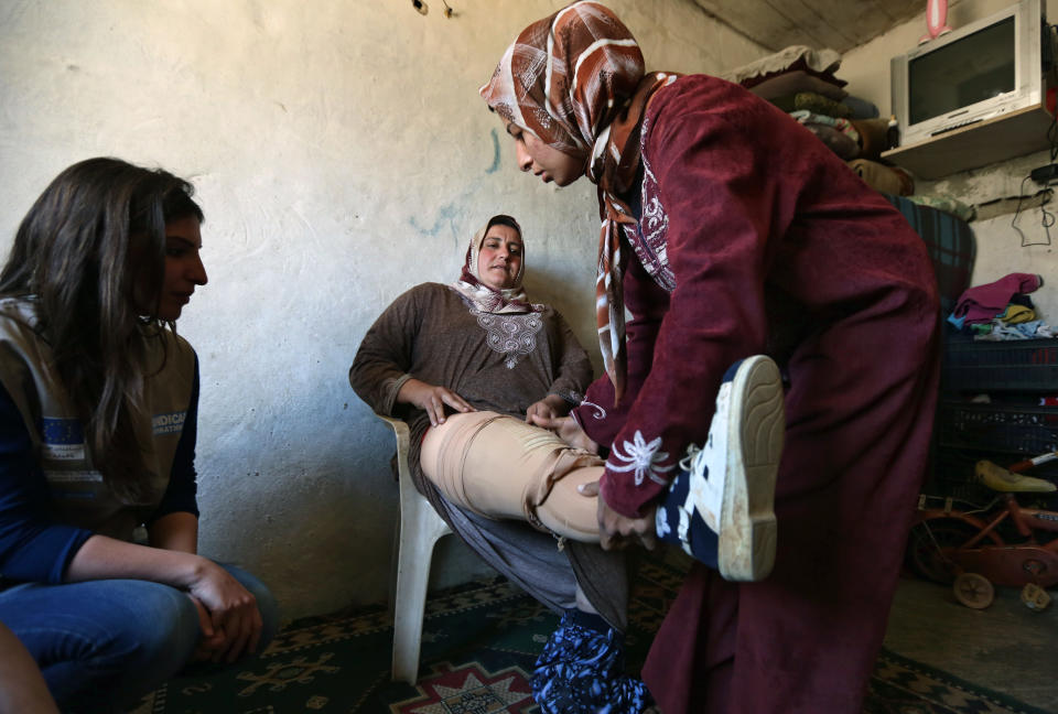 In this Thursday, March 27, 2014 photo, Reem Diab, 34, center, who lost her leg on Oct. 25, 2012 when a shell slammed into her house in the town of Khan Sheikoun in central Syria, takes off her artificial leg with the help of her relative, right, as Abeer Ameen, left, a physiotherapist for Handicap International observes, in Chtaoura, in the Bekaa valley, Lebanon. The shelling killed her husband, Mustafa, and her 15-year-old daughter, Batoul. Syria’s civil war, which entered its fourth year last month, has killed more than 150,000 people. An often overlooked figure is the number of wounded more than 500,000, according to the International Committee of the Red Cross. An untold number of those, there’s no reliable estimate even, have suffered traumatic injuries that have left them physically handicapped. (AP Photo/Bilal Hussein)