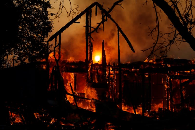 The sun is seen through a burning structure during the wind-driven Kincade Fire in Healdsburg, California