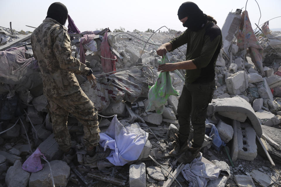 FILE - In this Oct. 27, 2019, file photo, people look at a destroyed houses near the village of Barisha, in Idlib province, Syria, after an operation by the U.S. military which targeted Abu Bakr al-Baghdadi, the shadowy leader of the Islamic State group. In his last months on the run, al-Baghdadi was agitated, fearful of traitors, sometimes disguised as a shepherd, sometimes hiding underground, always dependent on a shrinking circle of confidants. (AP Photo/Ghaith Alsayed, File)