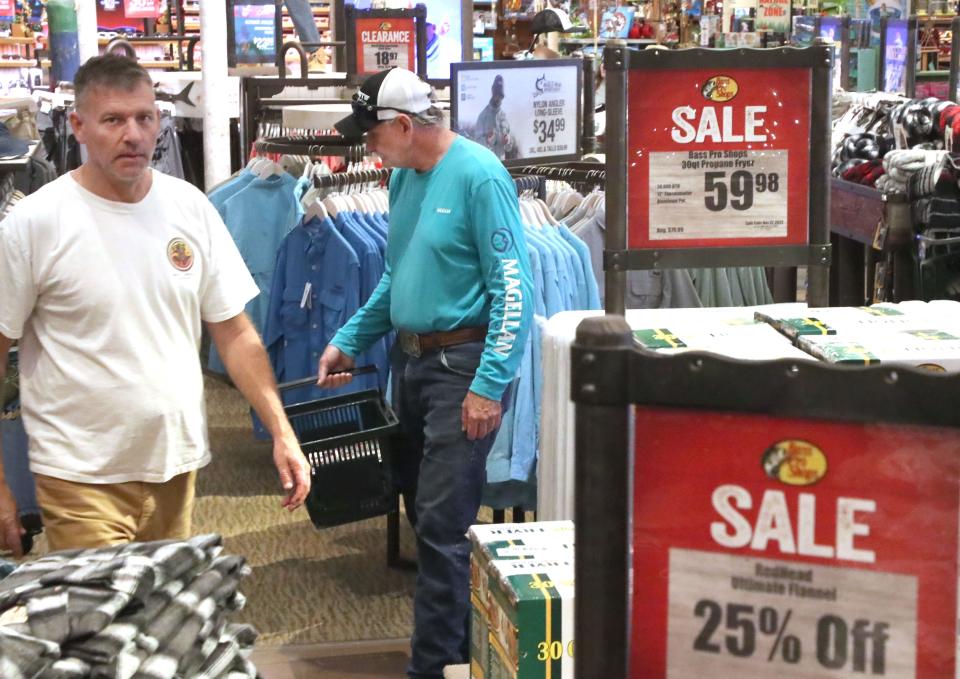 Shoppers stroll the aisles past sale and clearance signs at the Bass Pro Shops at One Daytona in Daytona Beach. Although many shoppers started making holiday purchases early this year, retailers still expect big crowds for Black Friday, the traditional start of the holiday shopping season.
