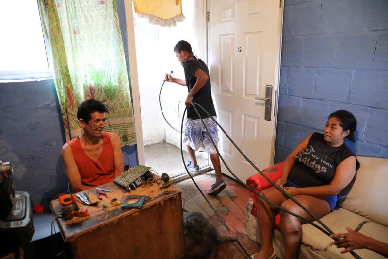 Henry pulls out of his house a hose after fills his plastic tank, filled with water by a community-made pipe system that extract water that accumulated at a stalled tunnel construction project near El Avila mountain that borders the city of Caracas