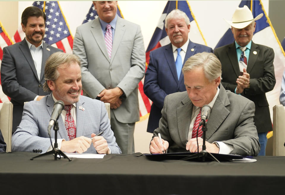Texas Gov Greg Abbott signs Senate Bill 1, also known as the election integrity bill, into law with State Sen. Bryan Hughes, R-Mineola, front center left, looking on with others in the background in Tyler, Texas, Tuesday, Sept. 7, 2021. The sweeping bill signed Tuesday by the two-term Republican governor further tightens Texas’ strict voting laws.(AP Photo/LM Otero)