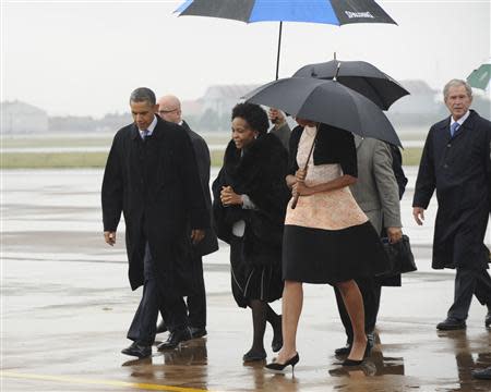 U.S. President Barack Obama (C) and former U.S. President George Bush (R) are greeted by officials on their arrival at Air Force Base Waterkloof, Pretoria in this handout picture provided by the South African Government Communication and Information System (GCIS) on December 10, 2013. REUTERS/GCIS/Handout via Reuters