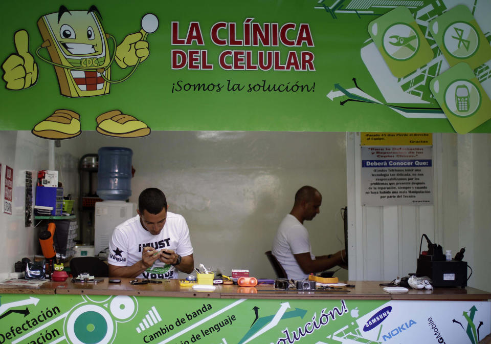 In this June 13, 2012 photo, Javier E. Matos, left, repairs a phone at The Cell Phone Clinic, a private business in Havana. For decades, Communist-run Cuba has essentially been free of commercial advertising. But it's a knotty problem for thousands of budding entrepreneurs who have embraced President Raul Castro's push for limited free-market reform. So they're turning to guerrilla marketing. (AP Photo/Franklin Reyes)